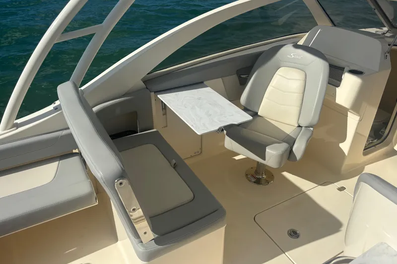 Slide: The Image of 2024 Scout 240 Dorado boat interior with seating and table, on calm water. - 12