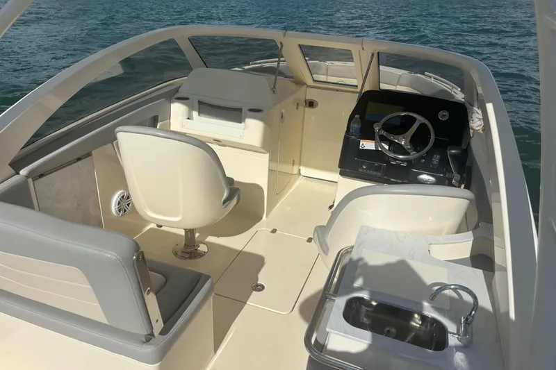 Slide: The Image of 2024 Scout 240 Dorado boat interior with helm, seating, and sink, on water. - 13