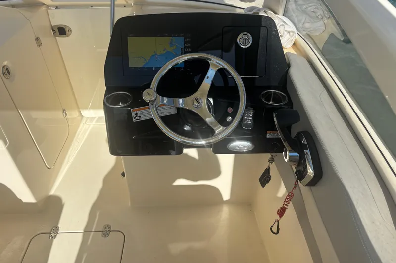 Slide: The Image of 2024 Scout 240 Dorado boat helm with steering wheel and navigation display. - 14