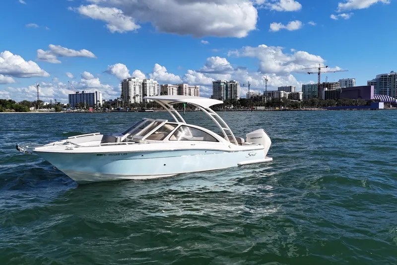 Slide: The Image of 2024 Scout 240 Dorado boat cruising on water with city skyline in background. - 2