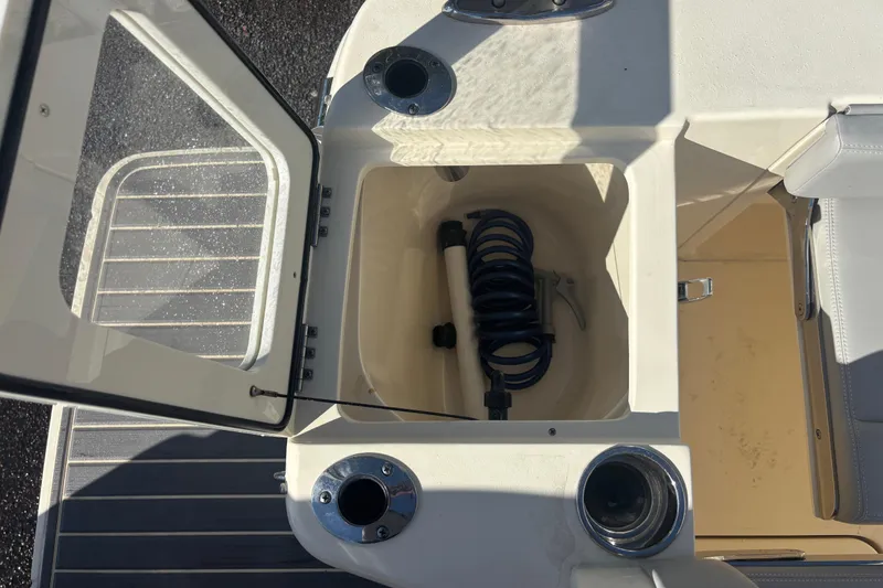 Slide: The Image of Open storage compartment on 2024 Scout 240 Dorado boat with coiled hose inside. - 22