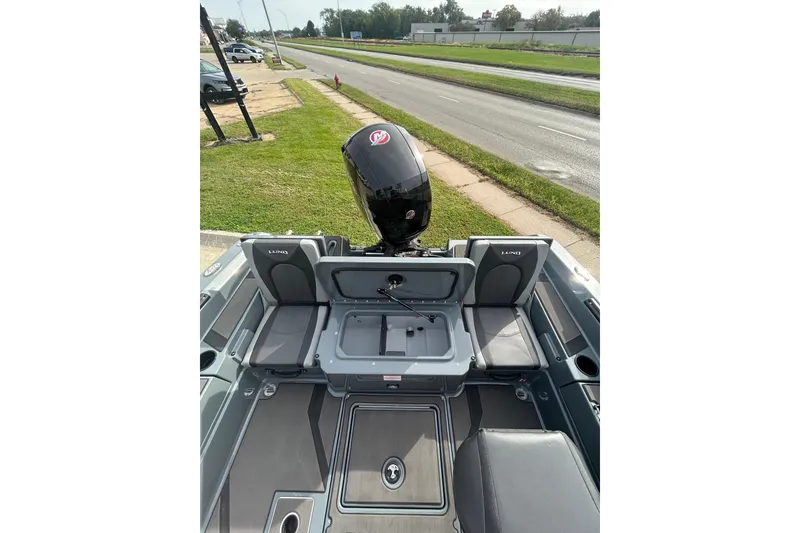 Slide: The Image of 2026 Lund 185 Impact GL boat interior with seating and motor, parked near a road. - 26