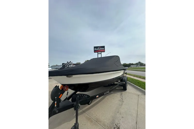 Slide: The Image of Covered 2026 Lund 185 Impact GL boat on trailer, parked near Safelite AutoGlass sign. - 9