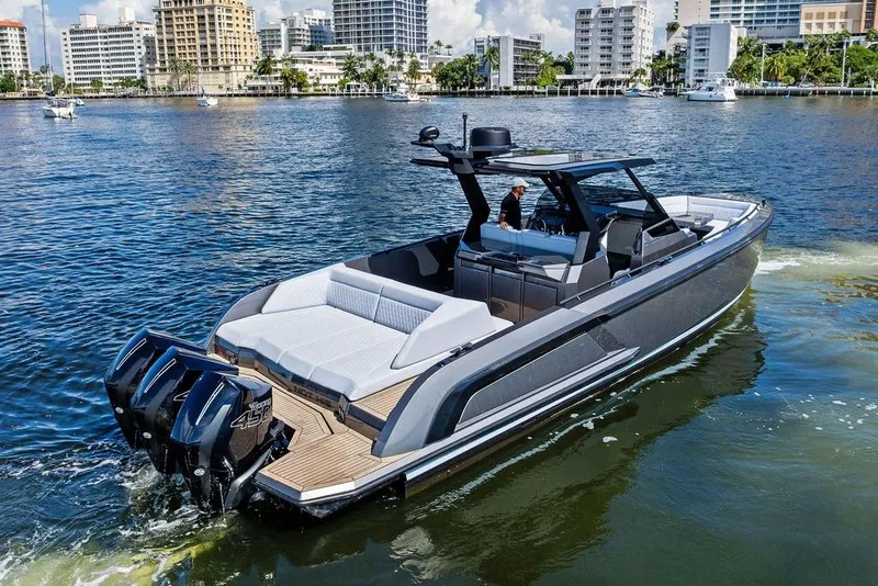 Slide: The Image of 2024 Vanquish Yachts 40 cruising on a sunny waterfront with modern buildings in the background. - 8