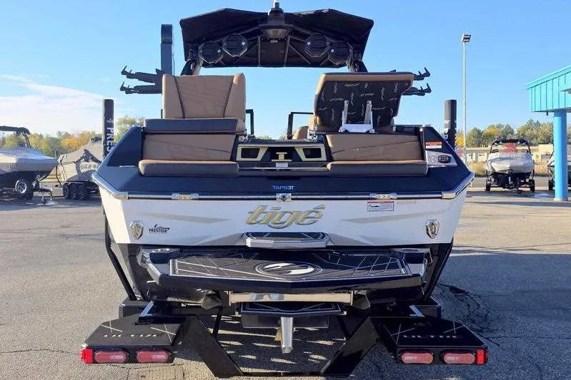 Slide: The Image of 2026 Tigé 25ZX boat rear view with seating and speakers in a parking lot. - 5