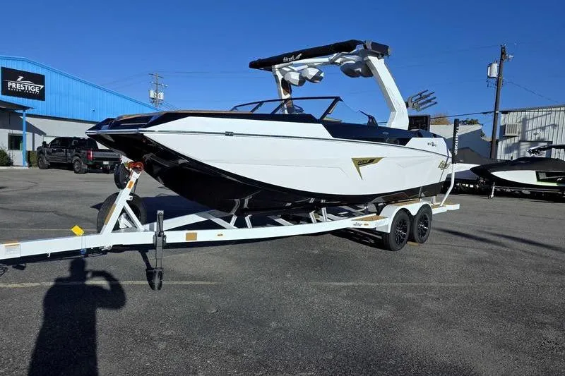 Slide: The Image of 2026 Tigé 22RZX boat on trailer in parking lot, blue building in background. - 3