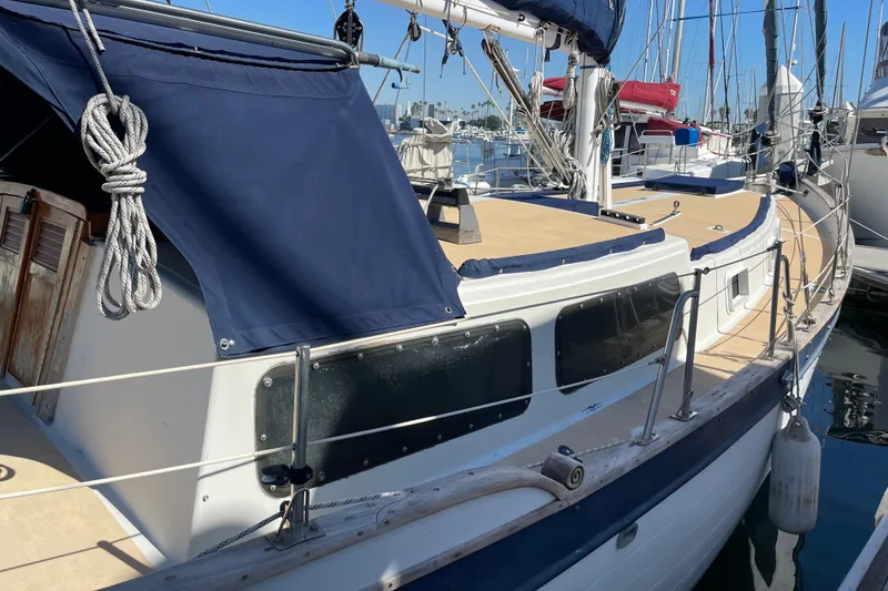 Slide: The Image of 1978 Downeast 38 sailboat docked, featuring blue canvas covers and wooden accents. - 10