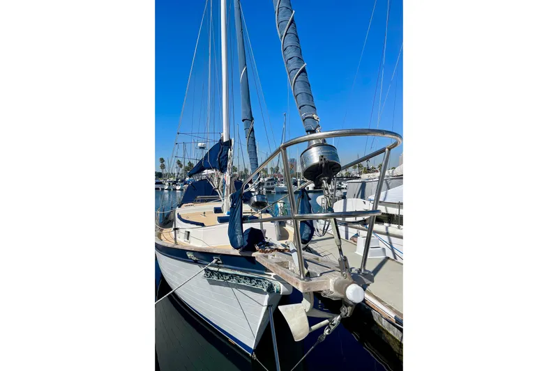 Slide: The Image of 1978 Downeast 38 sailboat docked, featuring blue sails and polished deck. - 2