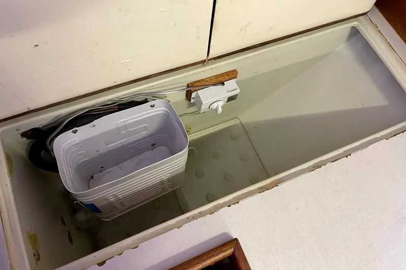 Slide: The Image of Storage compartment in a 1978 Downeast 38 boat with a white container and wiring. - 25