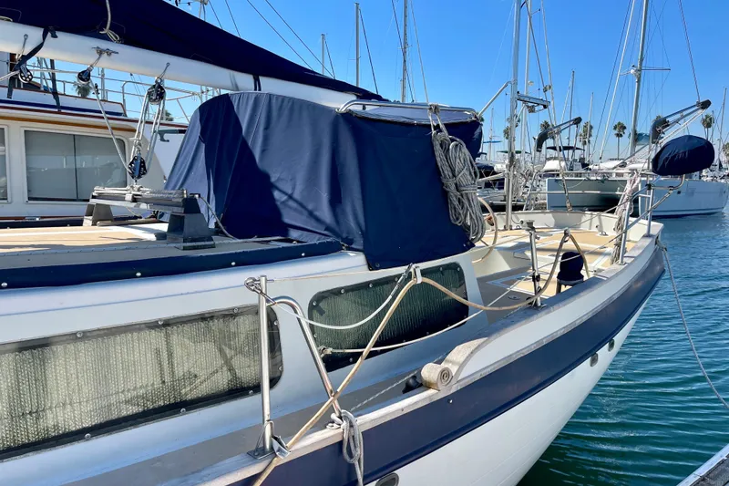 Slide: The Image of 1978 Downeast 38 sailboat docked in marina, featuring blue canvas covers and rigging. - 4