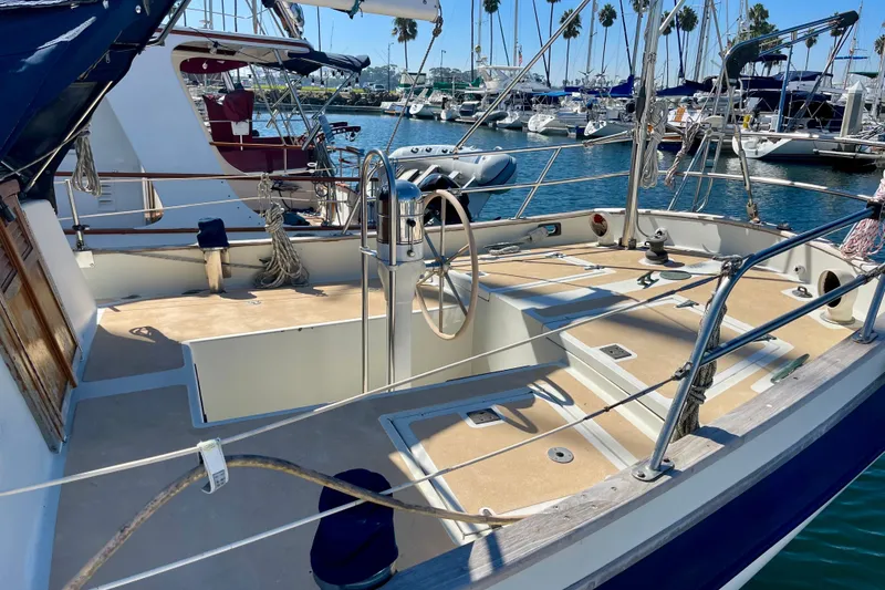 Slide: The Image of 1978 Downeast 38 sailboat cockpit with steering wheel, docked in a marina. - 6