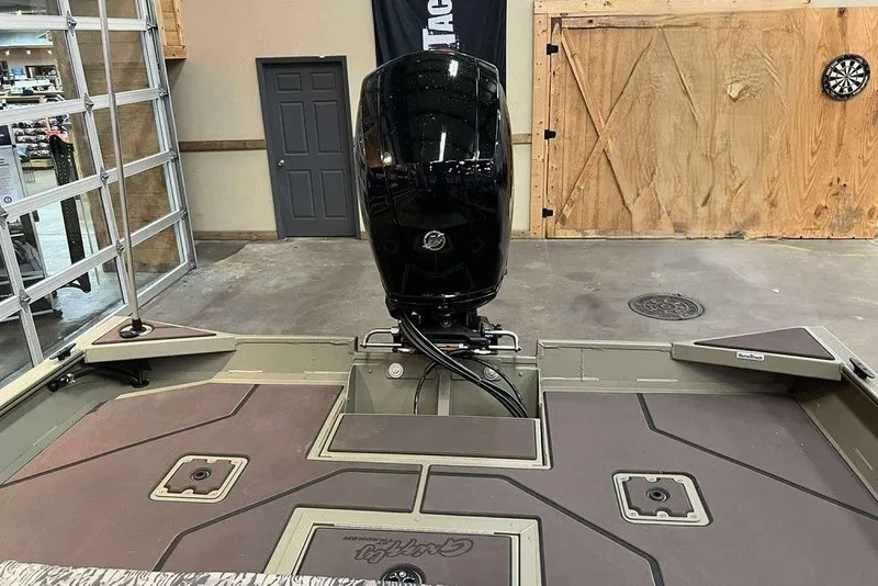 Slide: The Image of 2026 Tracker Grizzly 2072 CC boat interior with motor, in a showroom setting. - 8