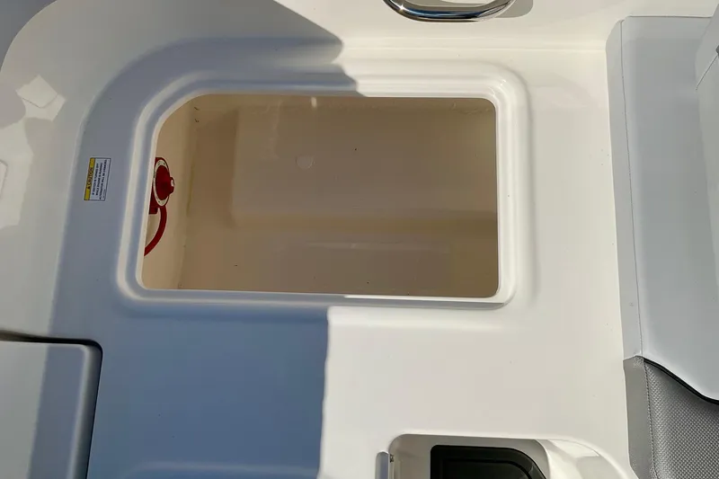 Slide: The Image of 2026 Bayliner VR6 Bowrider I/O storage compartment with red handle, white interior. - 22