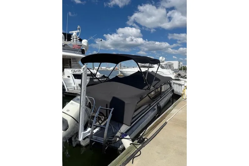 Slide: The Image of 2021 Godfrey Monaco 255 SFL pontoon boat docked under a clear blue sky. - 2