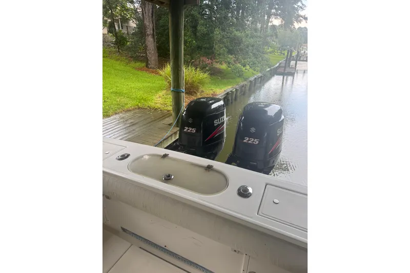 Slide: The Image of 2005 Regulator 26 Center Console with twin Suzuki 225 outboard motors docked by a lush shoreline. - 20