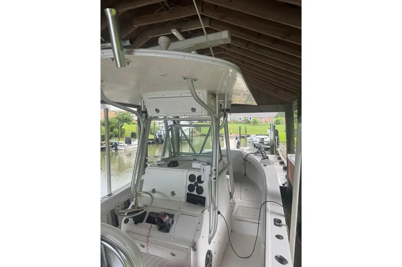 Slide: The Image of 2005 Regulator 26 Center Console boat docked under a wooden shelter. - 23
