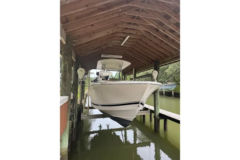 Slide: The Image of 2005 Regulator 26 Center Console boat docked under wooden shelter. - 25