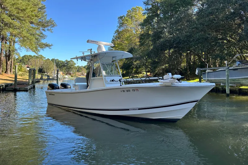 Slide: The Image of 2005 Regulator 26 Center Console boat on a calm waterway, surrounded by trees. - 3