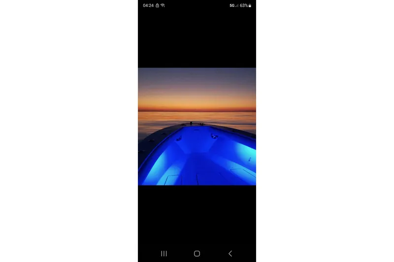 Slide: The Image of 2005 Regulator 26 Center Console boat with blue lights at sunset on calm water. - 31