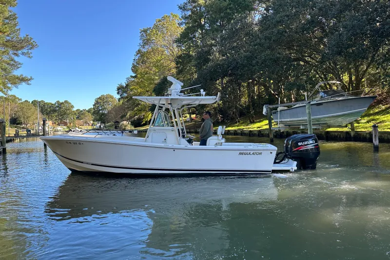 Slide: The Image of 2005 Regulator 26 Center Console boat on a calm waterway, surrounded by trees. - 5