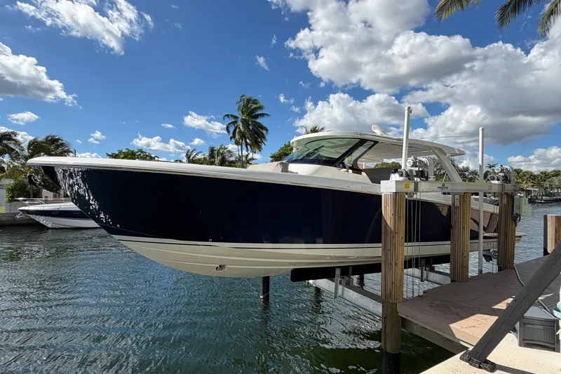 Slide: The Image of 2024 Tiara Yachts 43 LS on lift, docked by palm trees under a blue sky. - 40