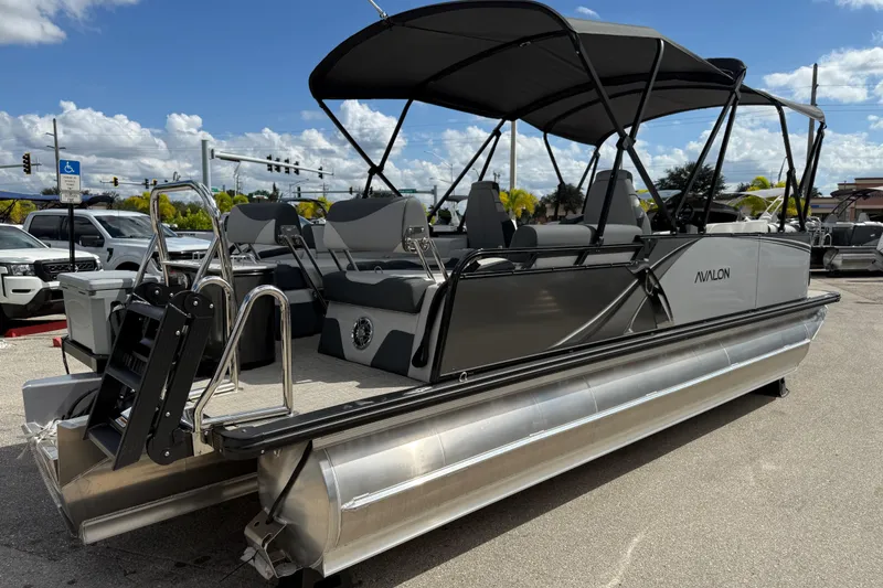 Slide: The Image of 2025 Avalon 2385 LSZ Quad Lounger Tri Toon boat with canopy, parked outdoors. - 5