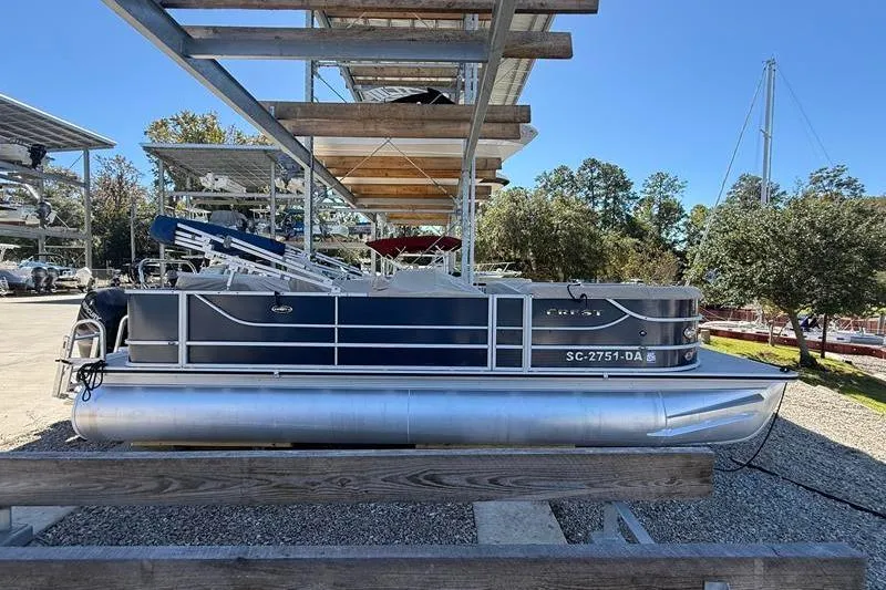 Slide: The Image of 2013 Crest Classic 230 SLC pontoon boat on dry dock, sunny day, outdoor storage. - 0
