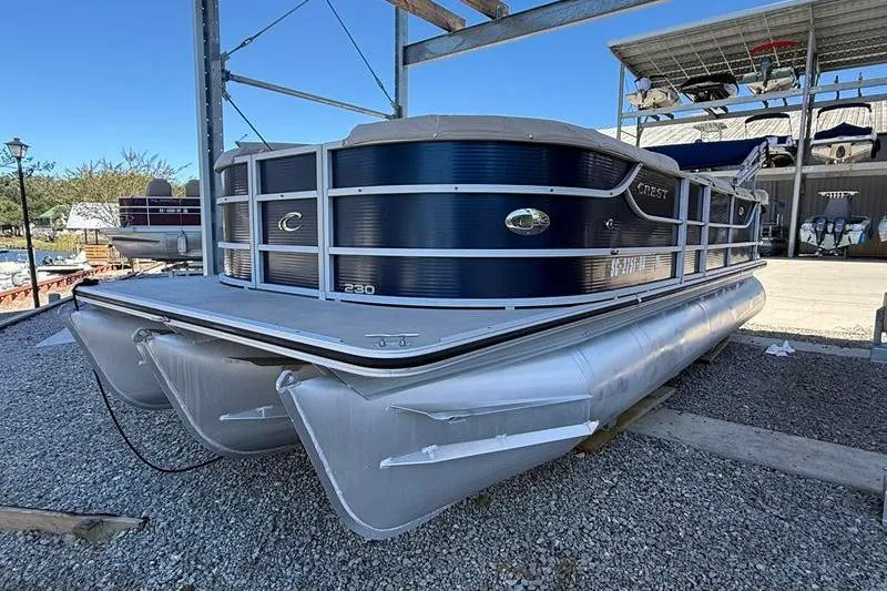 Slide: The Image of 2013 Crest Classic 230 SLC pontoon boat on gravel, under a metal structure. - 4