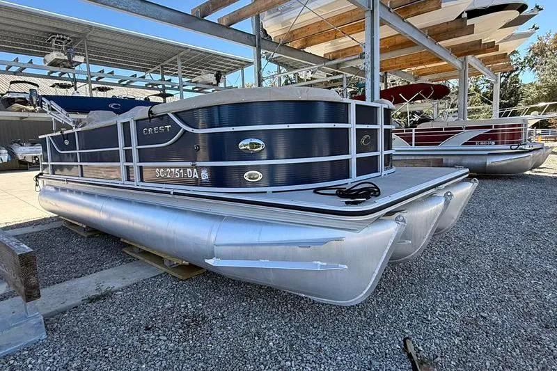 Slide: The Image of 2013 Crest Classic 230 SLC pontoon boat on gravel, under a metal canopy. - 6