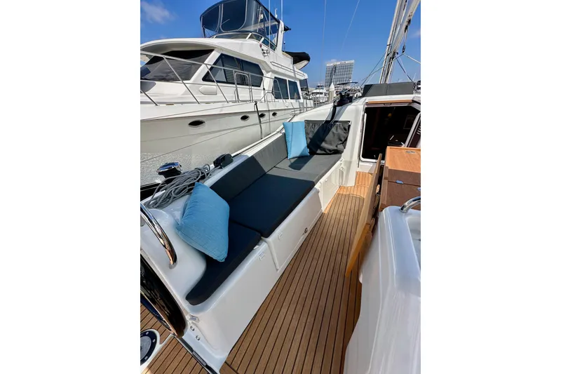 Slide: The Image of 2024 Jeanneau Sun Odyssey 410 yacht deck with cushioned seating and wooden flooring. - 64