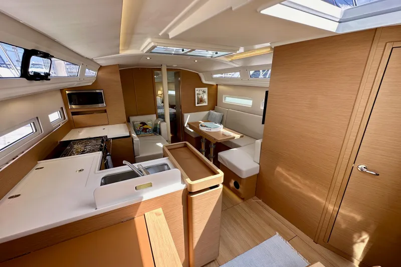 Slide: The Image of Interior of 2024 Jeanneau Sun Odyssey 410 yacht, featuring modern kitchen and seating area. - 79
