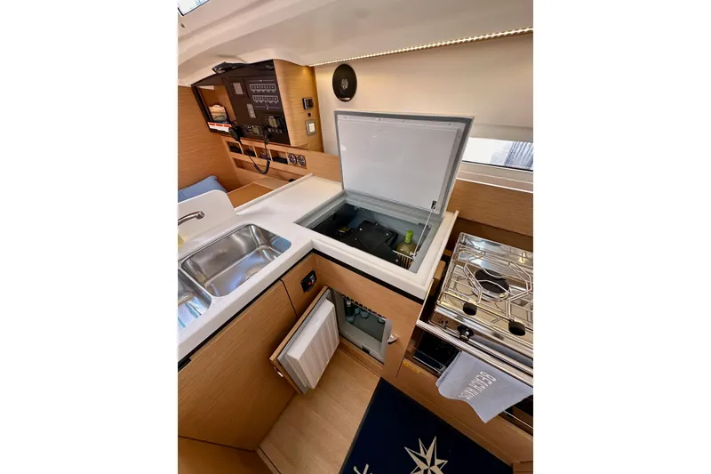 Slide: The Image of Modern kitchen interior of 2024 Jeanneau Sun Odyssey 410 yacht, featuring sink, stove, and storage. - 97