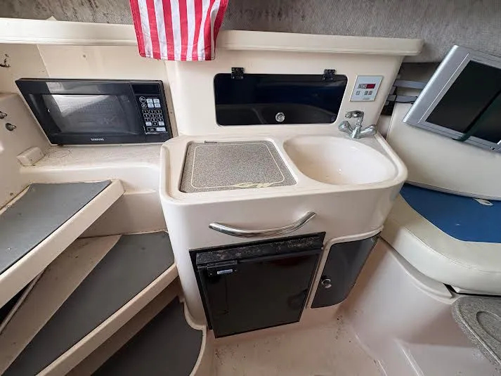Slide: The Image of 2002 Grady-White Marlin 300 boat interior with kitchenette, microwave, sink, and seating area. - 14
