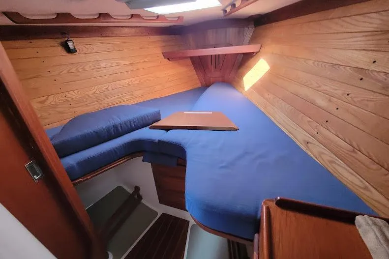 Slide: The Image of Cozy cabin interior of 1988 Freedom Yachts FREEDOM 36 with blue cushions and wooden paneling. - 22