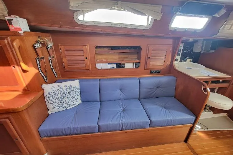 Slide: The Image of Interior of 1988 Freedom Yachts FREEDOM 36 with blue cushioned seating and wooden cabinetry. - 27