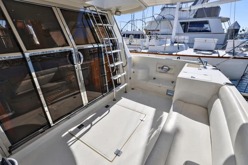 Slide: The Image of 2004 McKinna 57 Pilothouse yacht deck with seating, ladder, and marina view. - 14