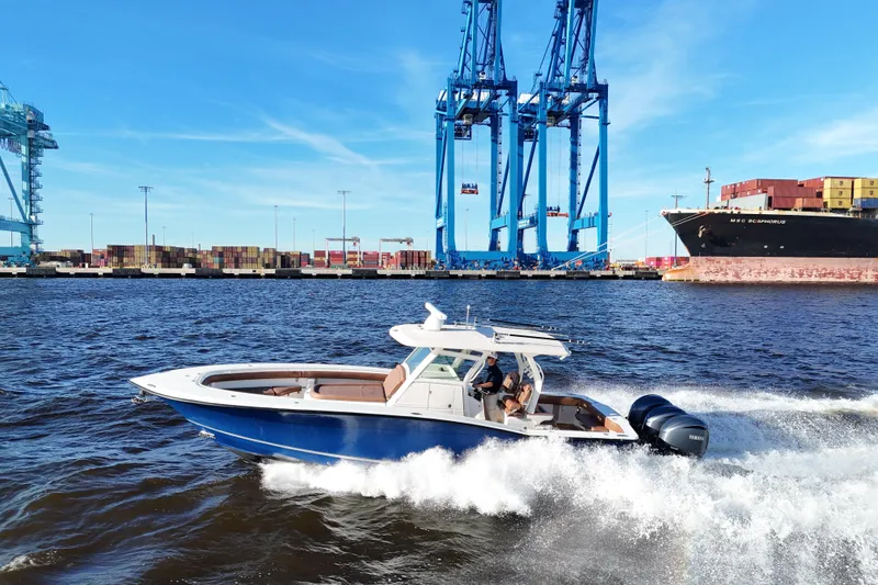 Slide: The Image of 2017 Scout 350 LXF boat cruising near shipping containers and cranes. - 21