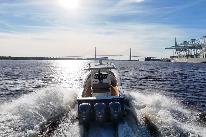 Slide: The Image of 2017 Scout 350 LXF boat cruising near a bridge and port under a sunny sky. - 25