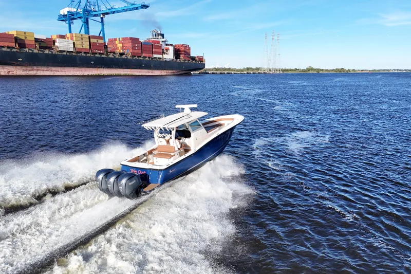 Slide: The Image of 2017 Scout 350 LXF boat cruising near a large cargo ship on a sunny day. - 27
