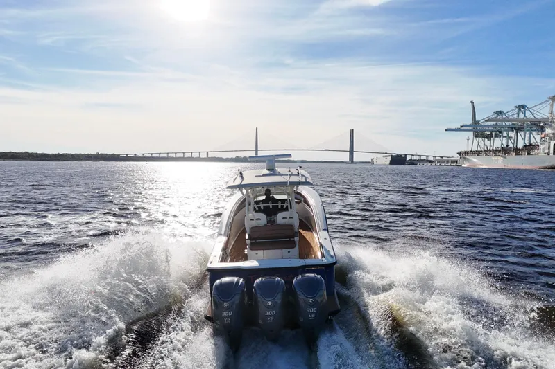 Slide: The Image of 2017 Scout 350 LXF boat cruising near a bridge and port under a sunny sky. - 37