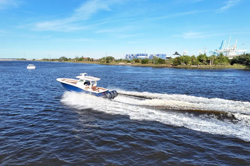 Slide: The Image of 2017 Scout 350 LXF boat cruising on a sunny day, creating waves in the water. - 38