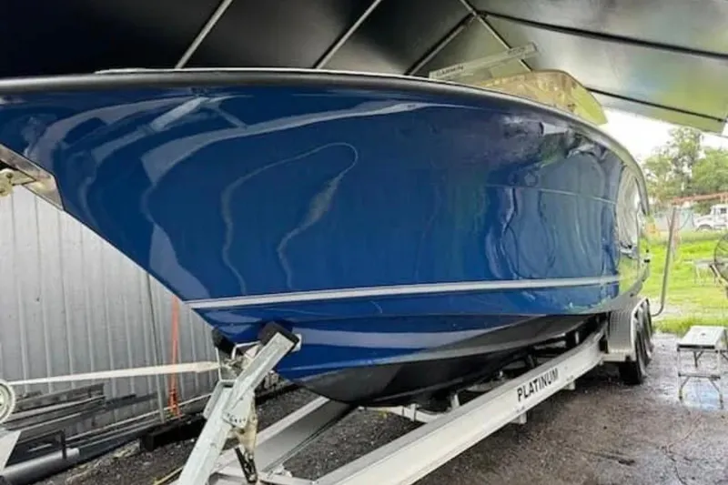 Slide: The Image of 2017 Scout 350 LXF boat in blue on a trailer under a canopy. - 52