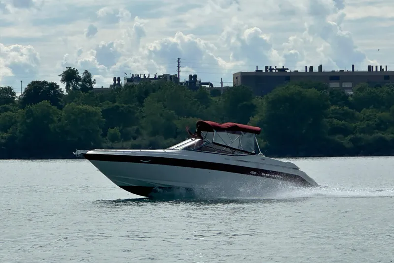 The Image of 1999 Regal 2850 LSC boat cruising on a lake with industrial buildings in the background. - 1