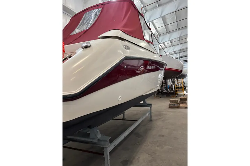 Slide: The Image of 1999 Regal 2850 LSC boat in storage, featuring maroon and white exterior. - 12