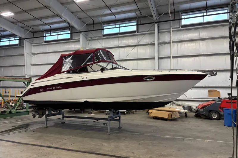 Slide: The Image of 1999 Regal 2850 LSC boat with maroon canopy in indoor storage facility. - 15