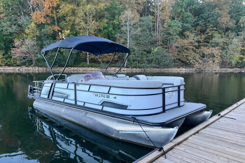 The Image of 2025 Starcraft EXS 3 Q DH pontoon boat docked on a serene lake with autumn foliage. - 0