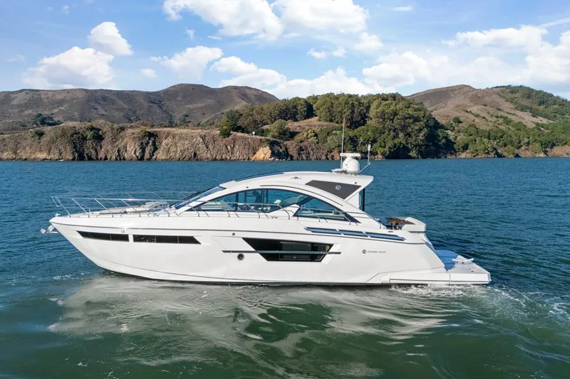 The Image of 2019 Cruisers Yachts 54 Cantius on scenic water with mountainous backdrop. - 0