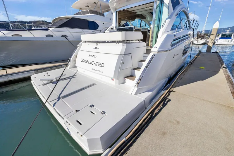 Slide: The Image of 2019 Cruisers Yachts 54 Cantius docked, rear view with "Simply Complicated" name visible. - 10