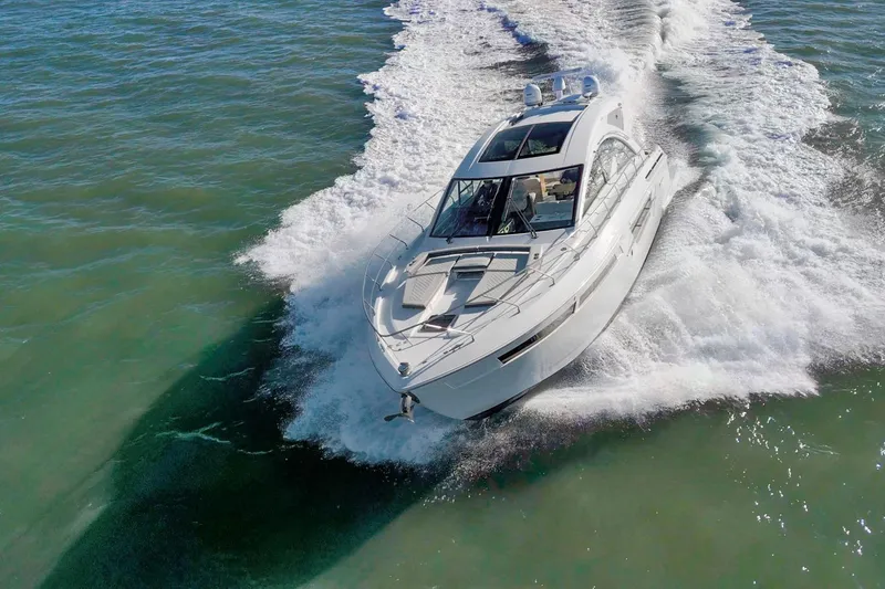 Slide: The Image of 2019 Cruisers Yachts 54 Cantius cruising on open water, creating a dynamic wake. - 105