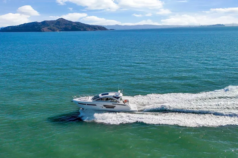 Slide: The Image of 2019 Cruisers Yachts 54 Cantius cruising on open water with scenic island backdrop. - 113
